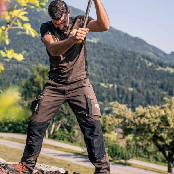 Ein Mann beim Auflockern eines Gartenbeetes mit Produkten von Terre Suisse.